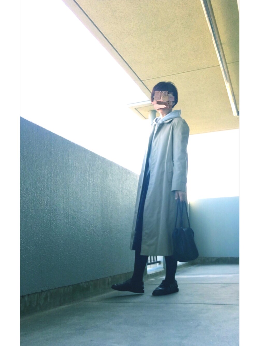 グレー系のパーカー、ベージュ系のステンカラーコート、ブルー系のスカートを着用したレディースの秋コーディネートの1枚目の写真