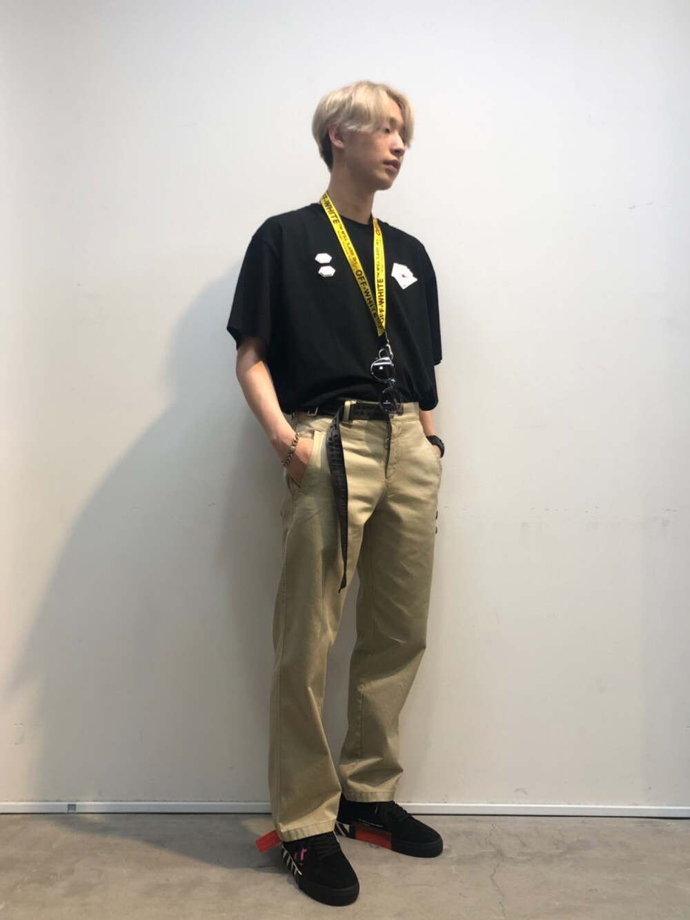 ブラック系のTシャツ/カットソー、ベージュ系のチノパンツ、ブラック系のスニーカーを着用したメンズの春コーディネートの1枚目の写真