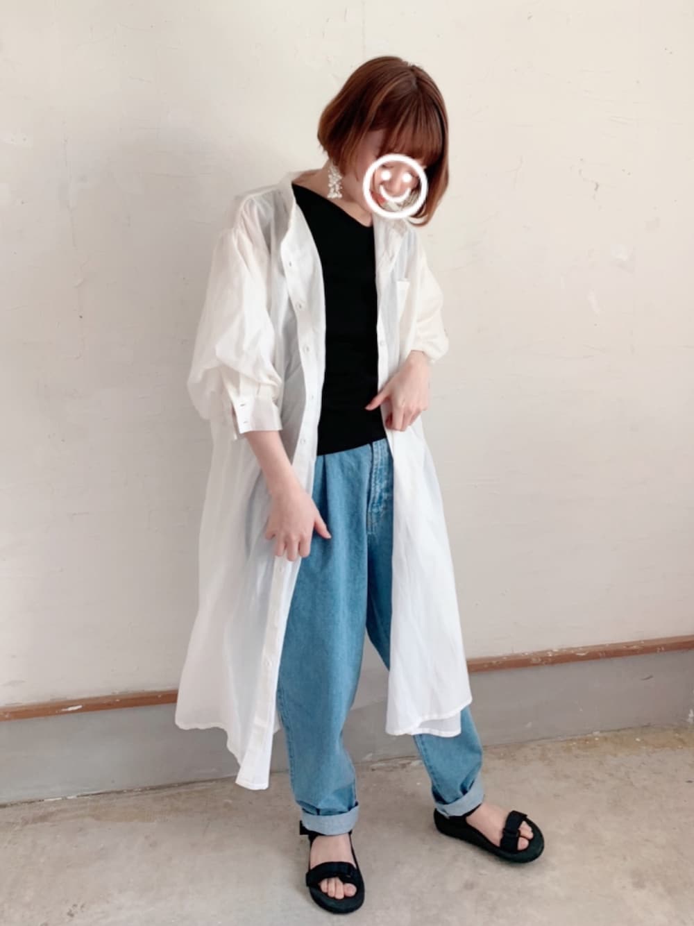 ホワイト系のシャツワンピース、ブルー系のデニムパンツ、ブラック系のサンダルを着用したレディースの春コーディネートの1枚目の写真