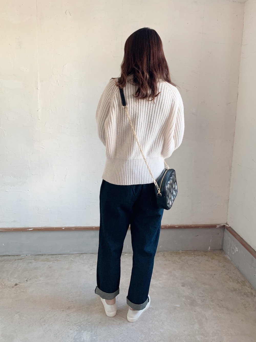 ベージュ系のニット/セーター、ブルー系のデニムパンツ、ホワイト系のスニーカーを着用したレディースの秋コーディネートの1枚目の写真