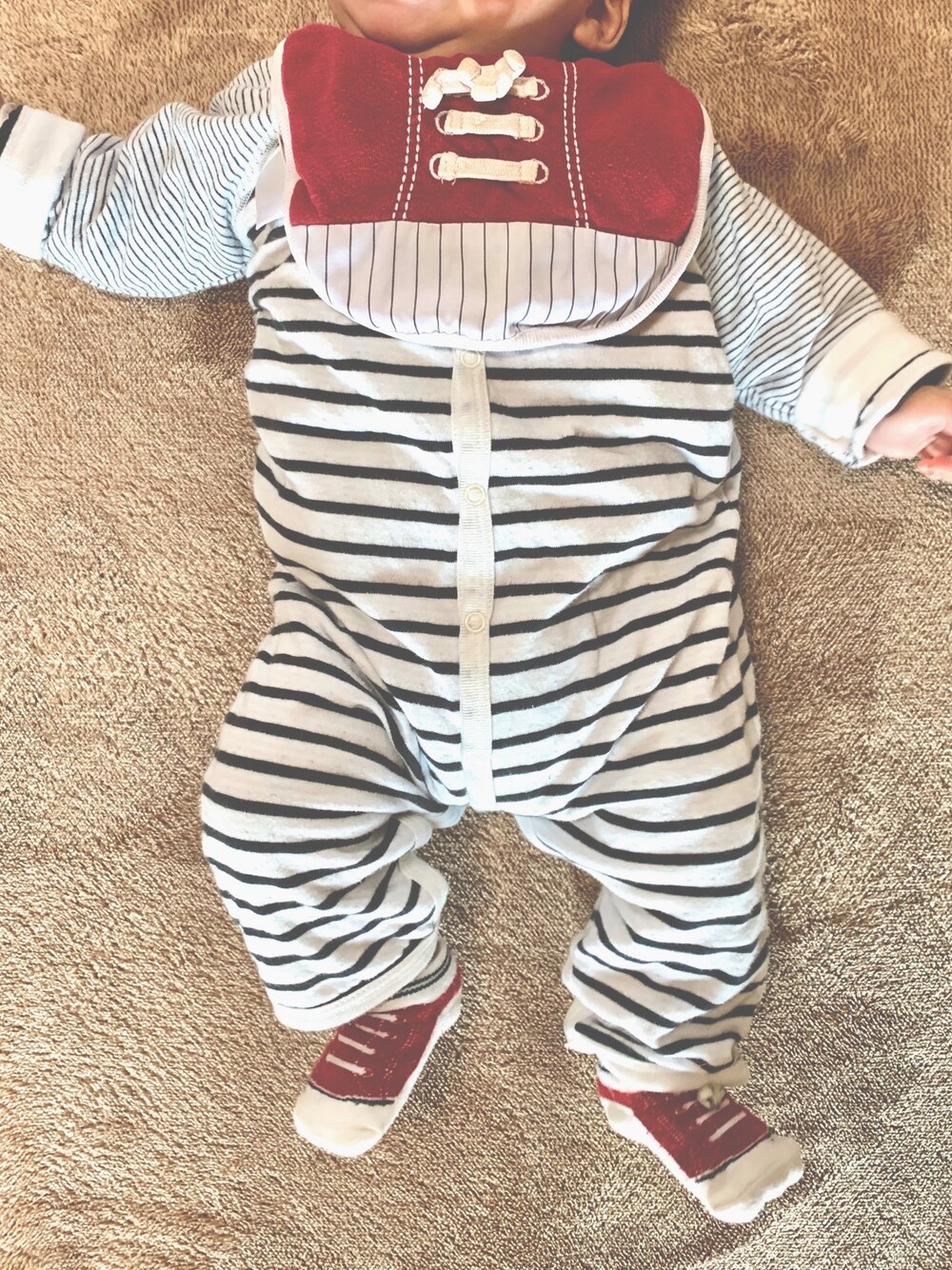 レッド系のスタイ/よだれかけ、ホワイト系のロンパース、レッド系のソックス/靴下を着用したキッズの春コーディネートの1枚目の写真