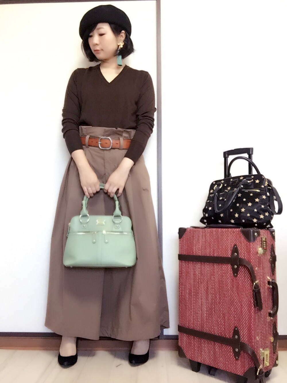 ブラウン系のニット/セーター、ベージュ系のその他パンツ、グリーン系のハンドバッグを着用したレディースの秋コーディネートの1枚目の写真