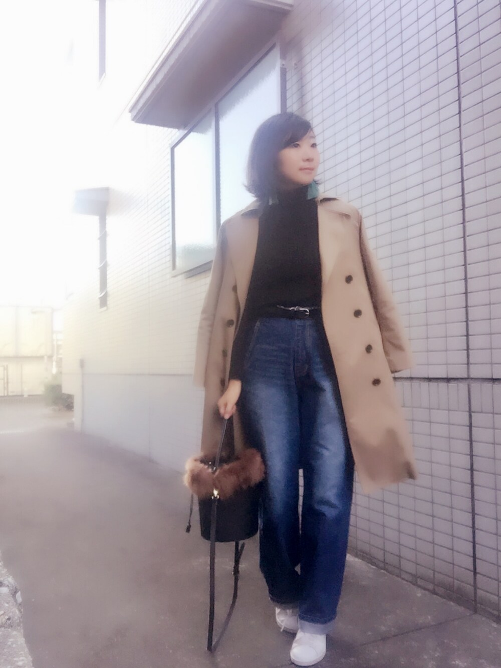 ベージュ系のトレンチコート、ブラック系のニット/セーター、ブルー系のデニムパンツを着用したレディースの秋コーディネートの1枚目の写真