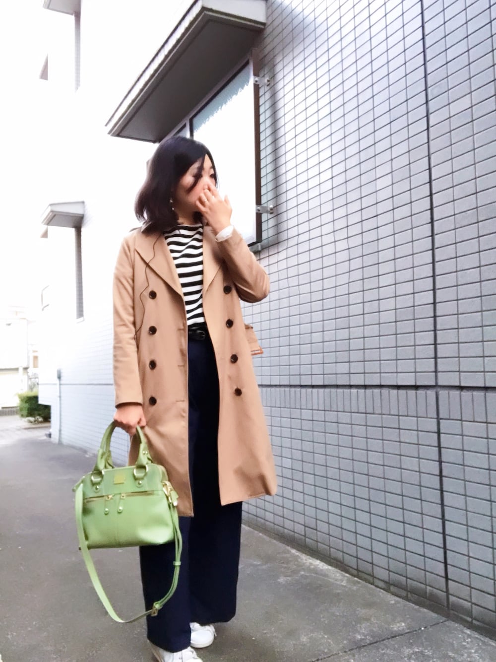 ベージュ系のトレンチコート、ホワイト系のTシャツ/カットソー、ブルー系のデニムパンツを着用したレディースの春コーディネートの1枚目の写真