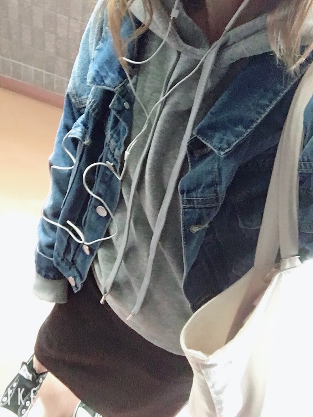 ブルー系のデニムジャケット、ブラック系のスカート、ブラック系のスニーカーを着用したレディースの秋コーディネートの1枚目の写真