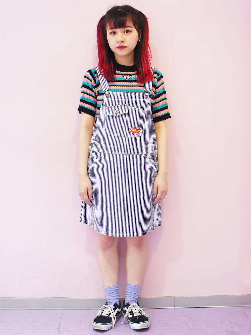 ブルー系のジャンパースカート、ブラック系のニット/セーター、ブラック系のスニーカーを着用したレディースの春コーディネートの1枚目の写真