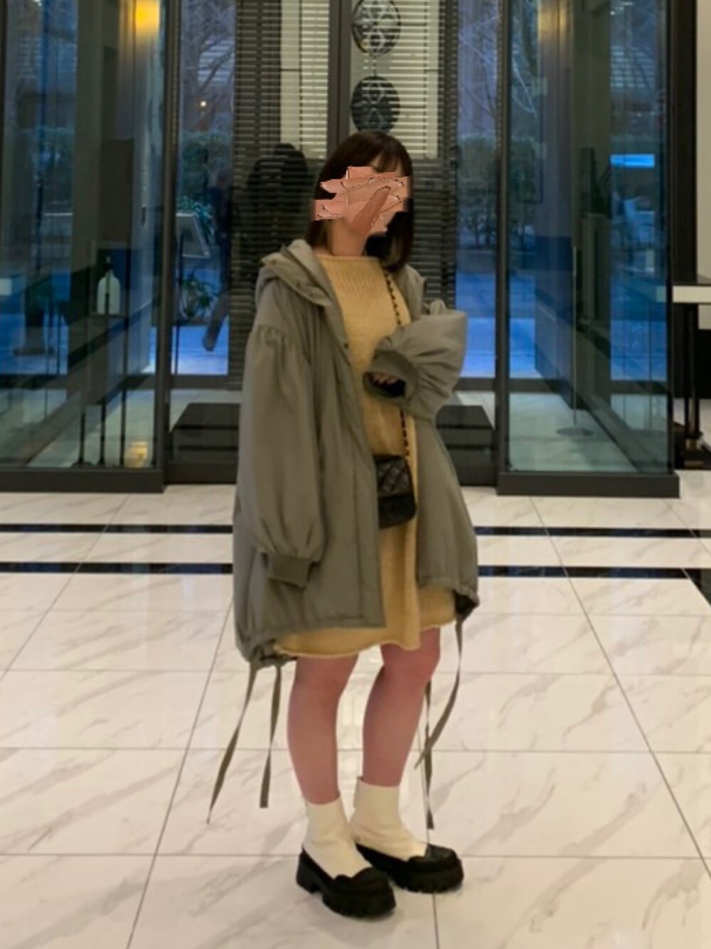 ホワイト系のブーツ、グリーン系のダウンジャケット/コート、ベージュ系のニット/セーターを着用したレディースの冬コーディネートの1枚目の写真