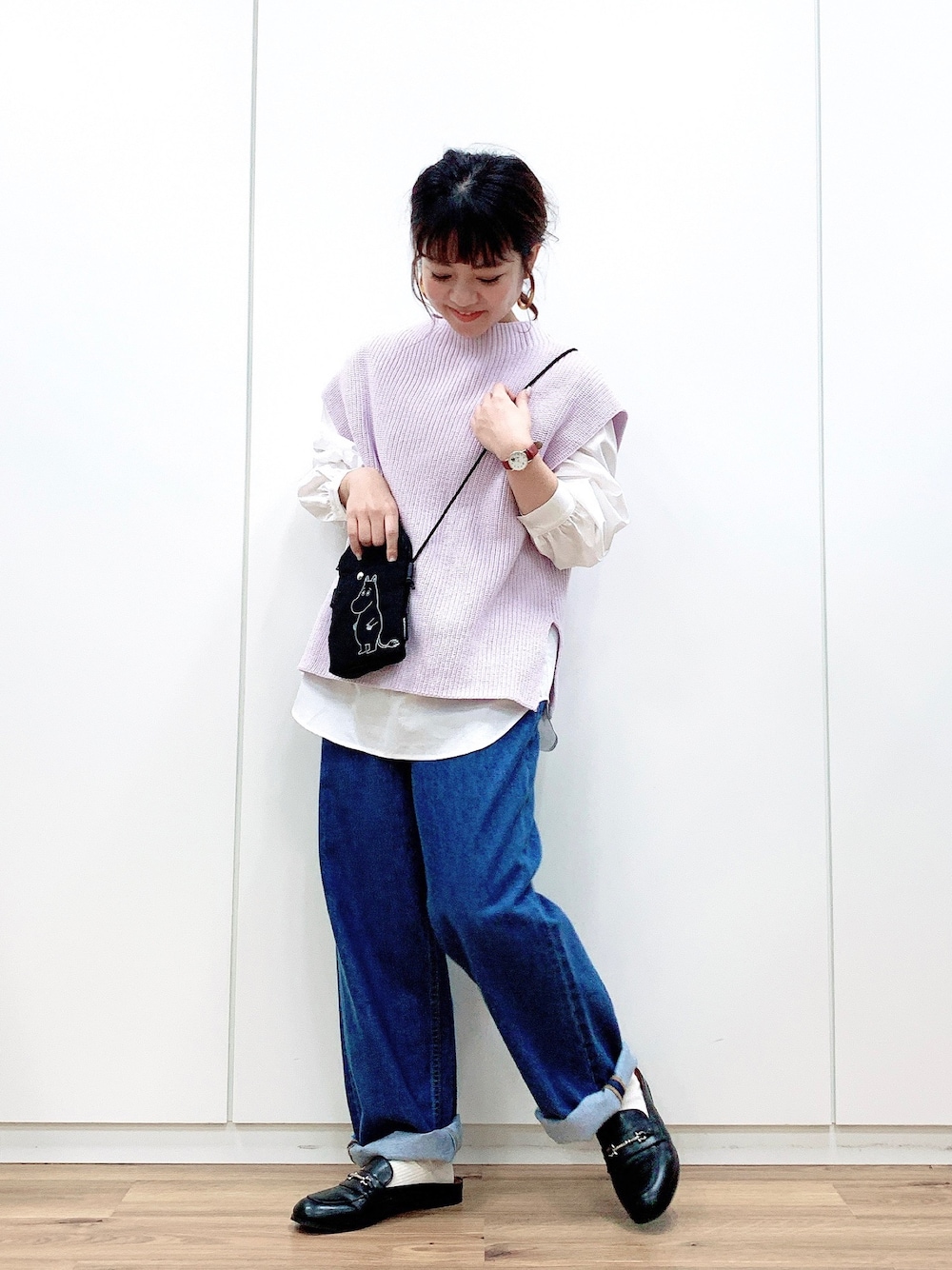 パープル系のベスト、ブルー系のデニムパンツ、ブラック系のショルダーバッグを着用したレディースの冬コーディネートの1枚目の写真