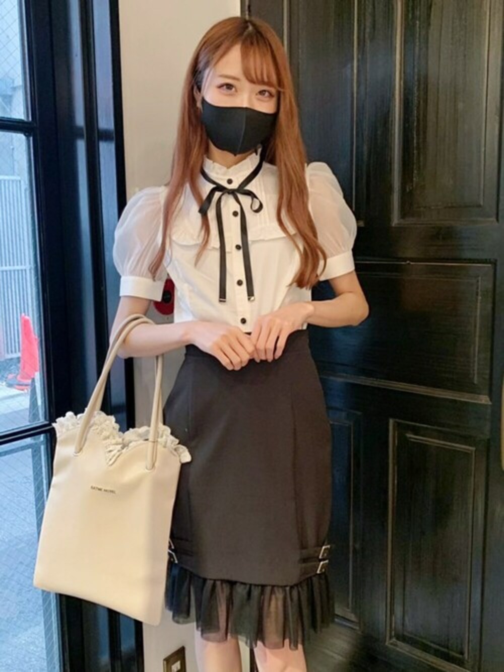 ブラック系のスカート、ホワイト系のシャツ/ブラウス、ベージュ系のトートバッグを着用したレディースの春コーディネートの1枚目の写真