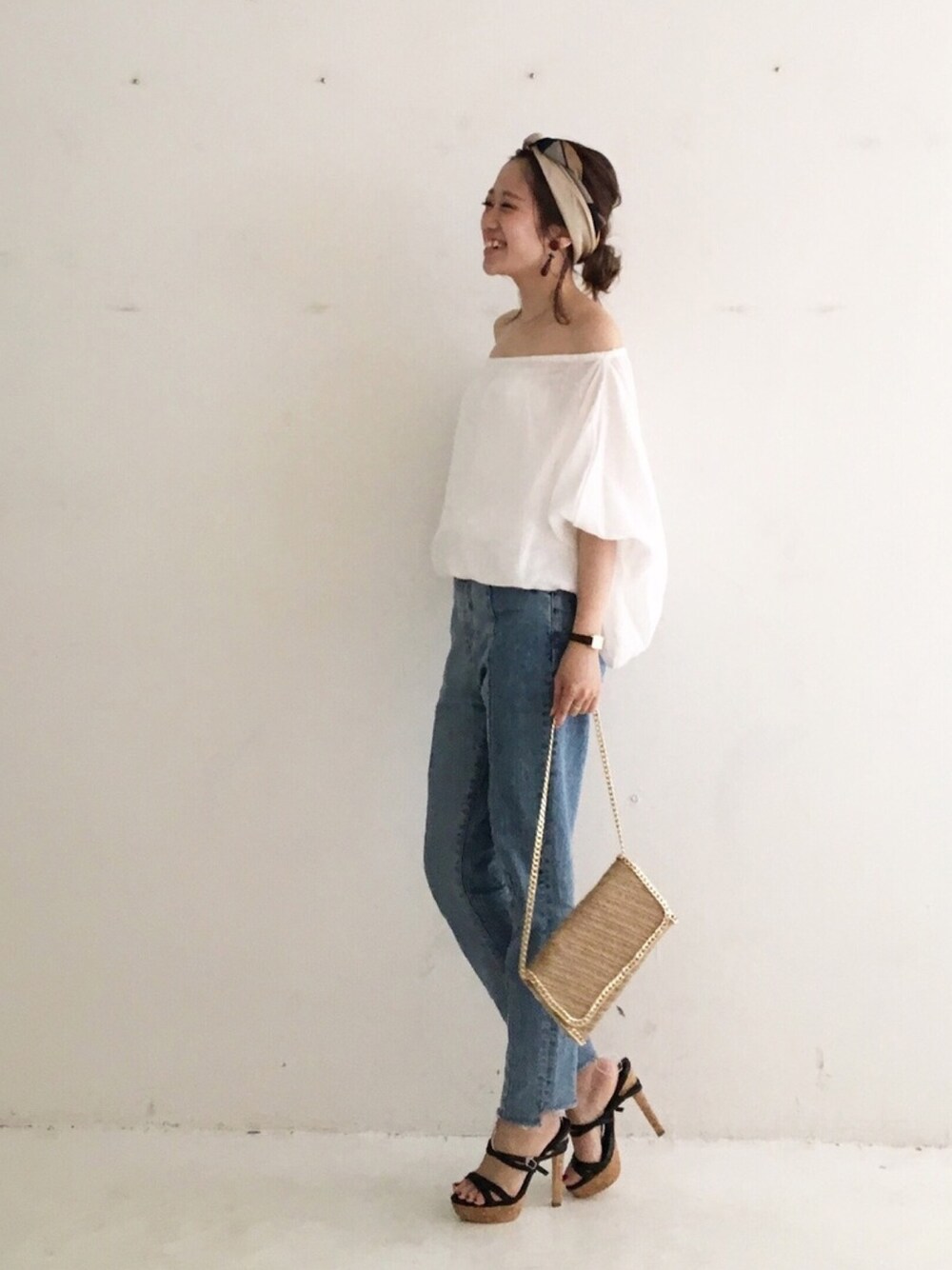 ブルー系のデニムパンツ、ベージュ系のショルダーバッグを着用したレディースの夏コーディネートの1枚目の写真