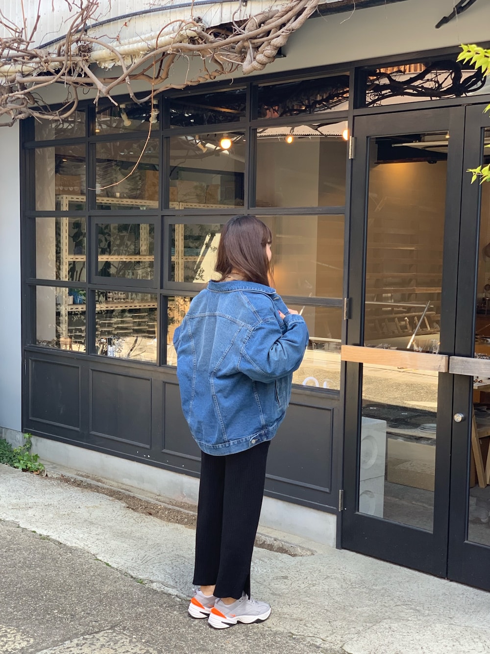 ブルー系のデニムジャケット、ブラック系のパンツ、グレー系のスニーカーを着用したレディースの春コーディネートの1枚目の写真