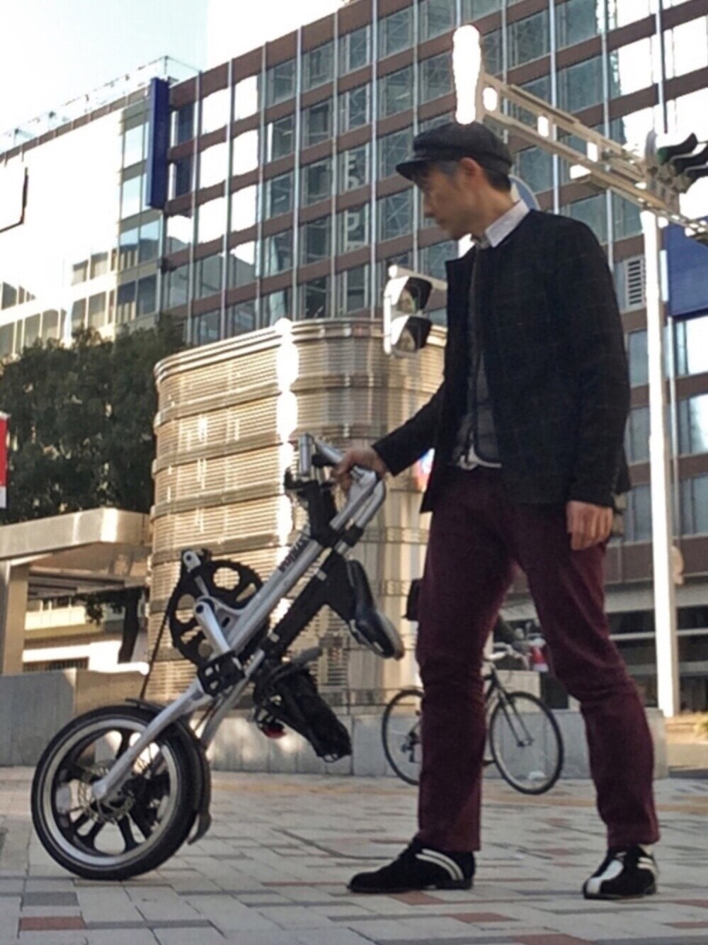 グレー系のベスト、ホワイト系のステンカラーコート、レッド系のその他パンツを着用したメンズの春コーディネートの1枚目の写真