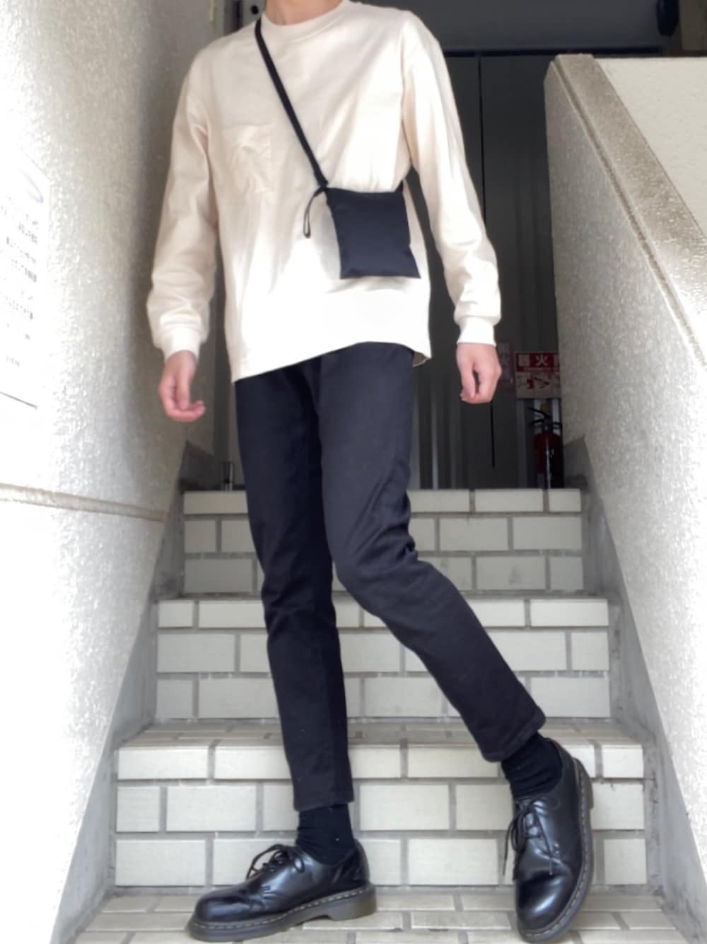 ベージュ系のTシャツ/カットソー、ブラック系のショルダーバッグ、ブラック系のデニムパンツを着用したメンズの春コーディネートの1枚目の写真