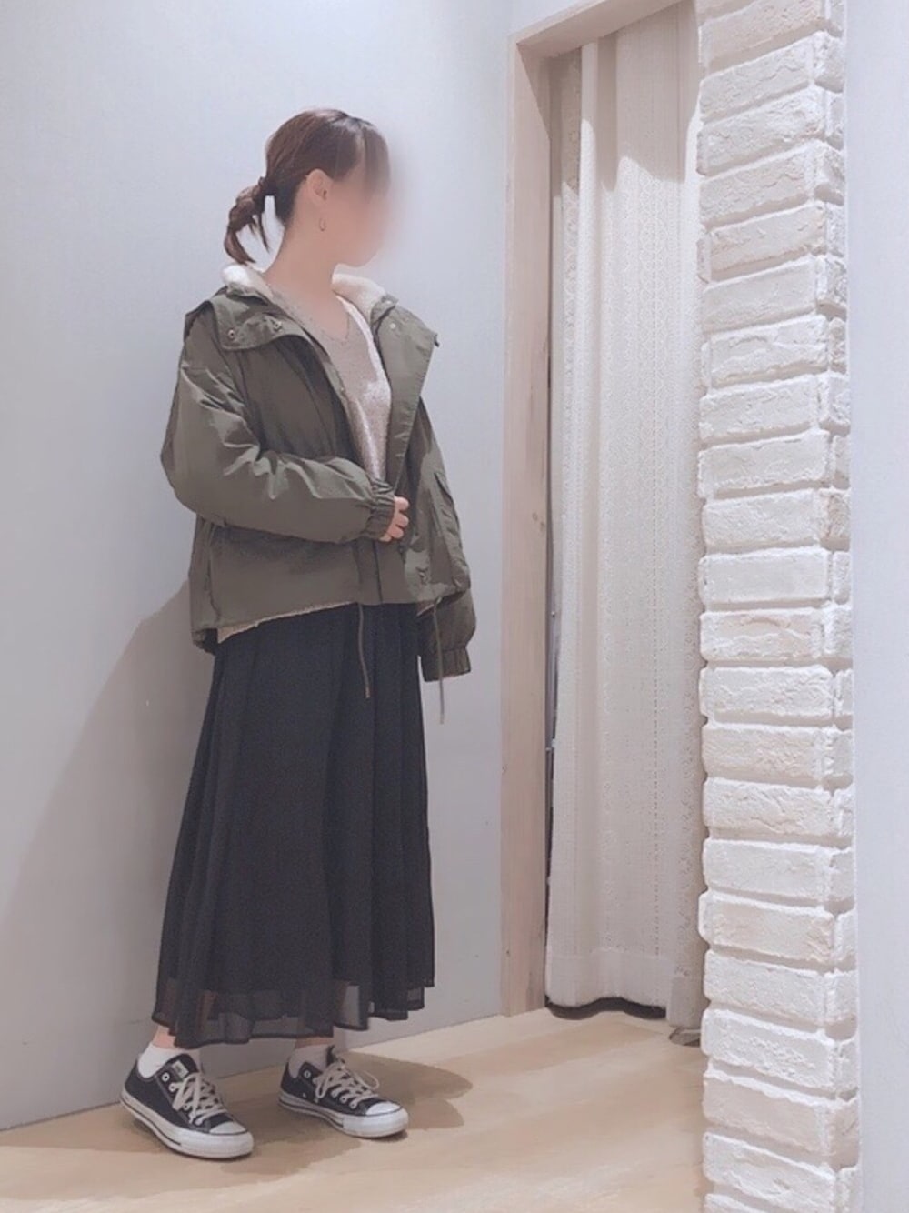 ブラック系のスカート、グリーン系のマウンテンパーカー、ベージュ系のニット/セーターを着用したレディースの秋コーディネートの1枚目の写真