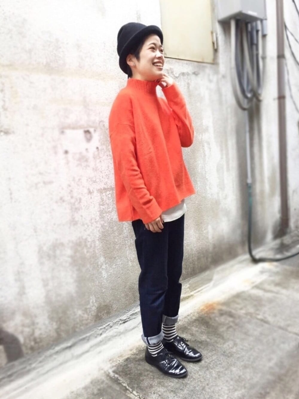 オレンジ系のニット/セーター、ブルー系のデニムパンツ、ブラック系のハットを着用したレディースの冬コーディネートの1枚目の写真