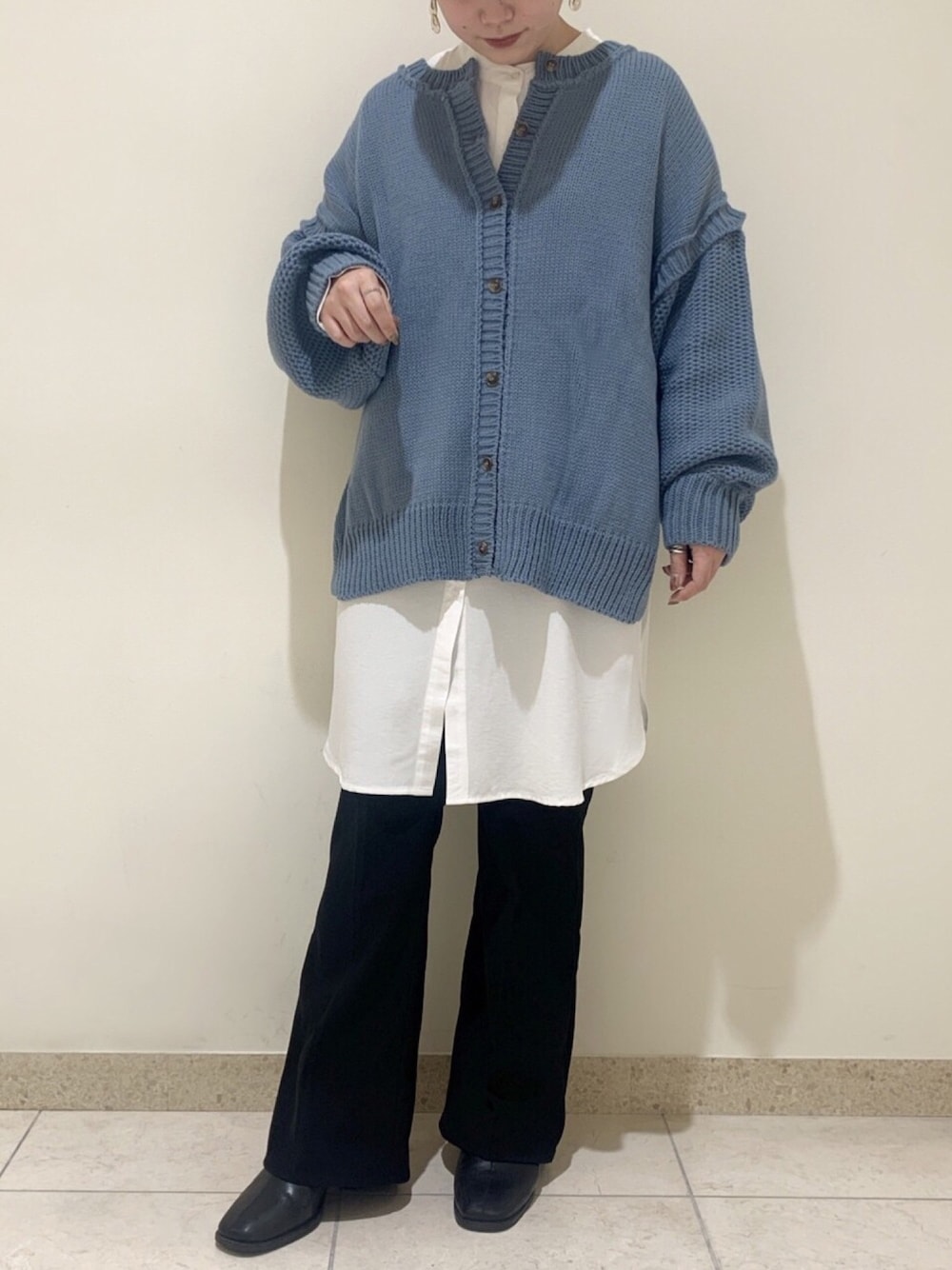 ブルー系のニット/セーター、ブラック系のスラックス、ホワイト系のシャツ/ブラウスを着用したレディースの冬コーディネートの1枚目の写真