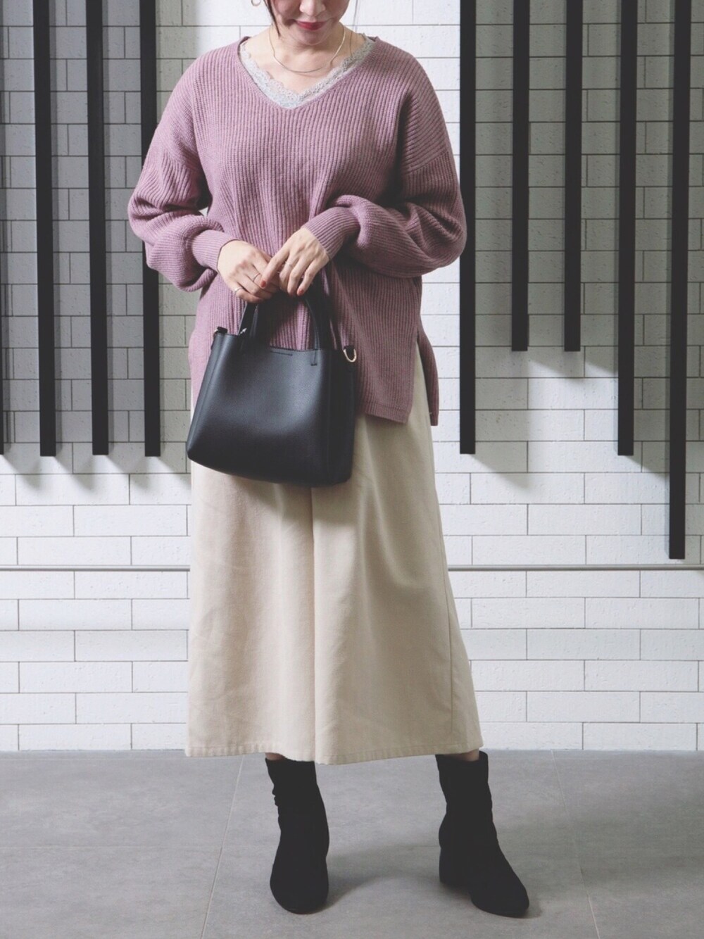 ピンク系のニット/セーター、ベージュ系のその他パンツ、ブラック系のショルダーバッグを着用したレディースの秋コーディネートの1枚目の写真