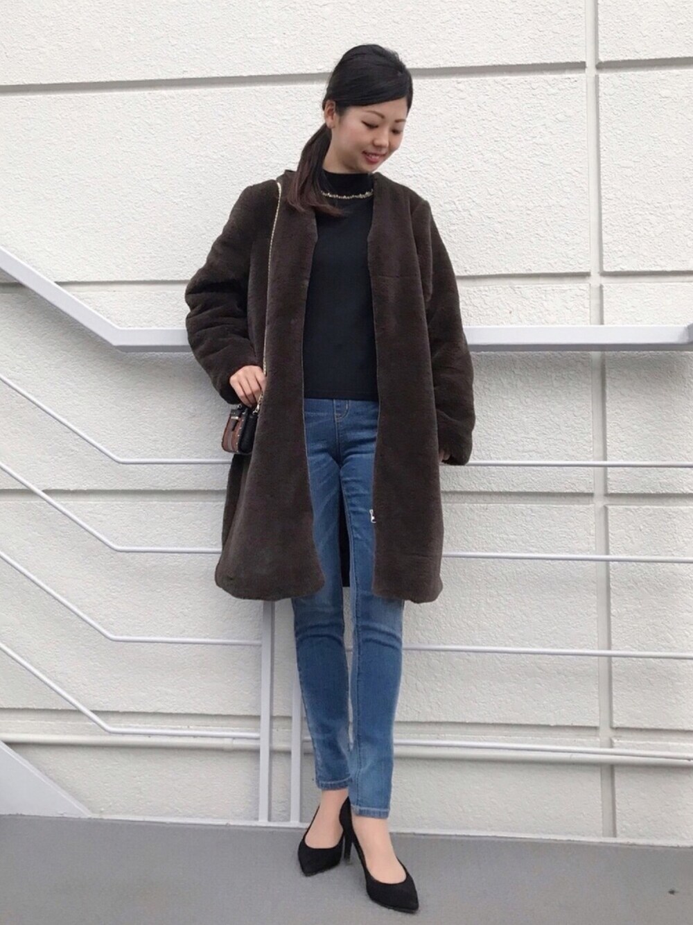 ブラック系のニット/セーター、ブルー系のその他パンツ、ブラウン系のバッグを着用したレディースの秋コーディネートの1枚目の写真