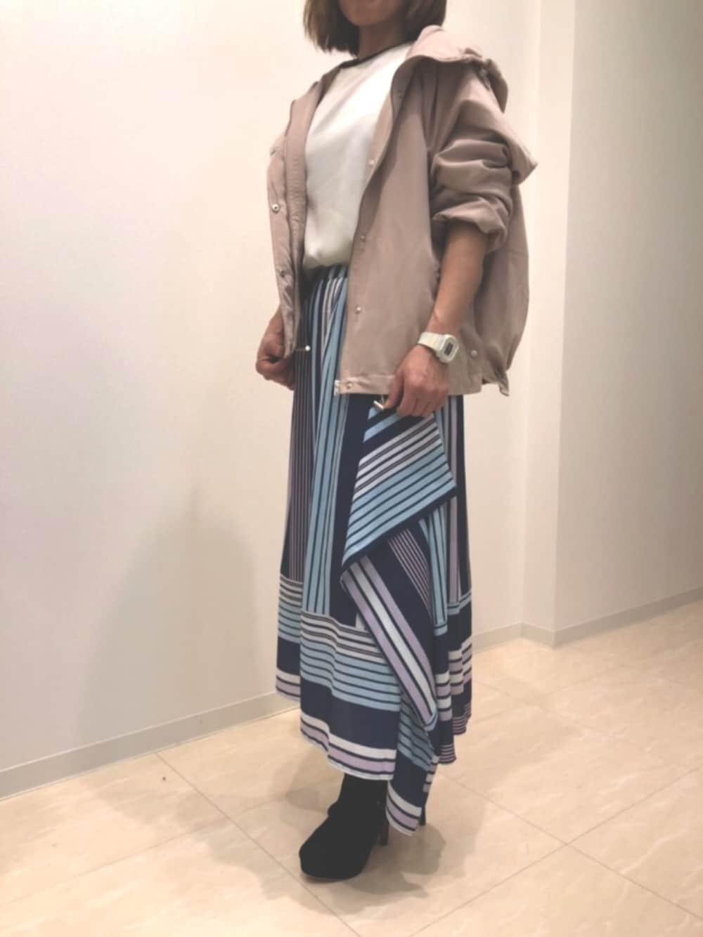 ブルー系のスカート、ピンク系のマウンテンパーカー、ホワイト系のニット/セーターを着用したレディースの春コーディネートの1枚目の写真