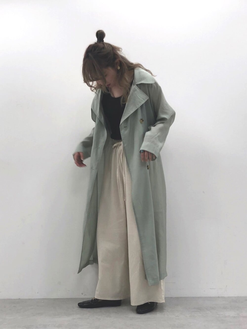 グリーン系のトレンチコート、ホワイト系のその他パンツ、ブラウン系のタンクトップを着用したレディースの春コーディネートの1枚目の写真