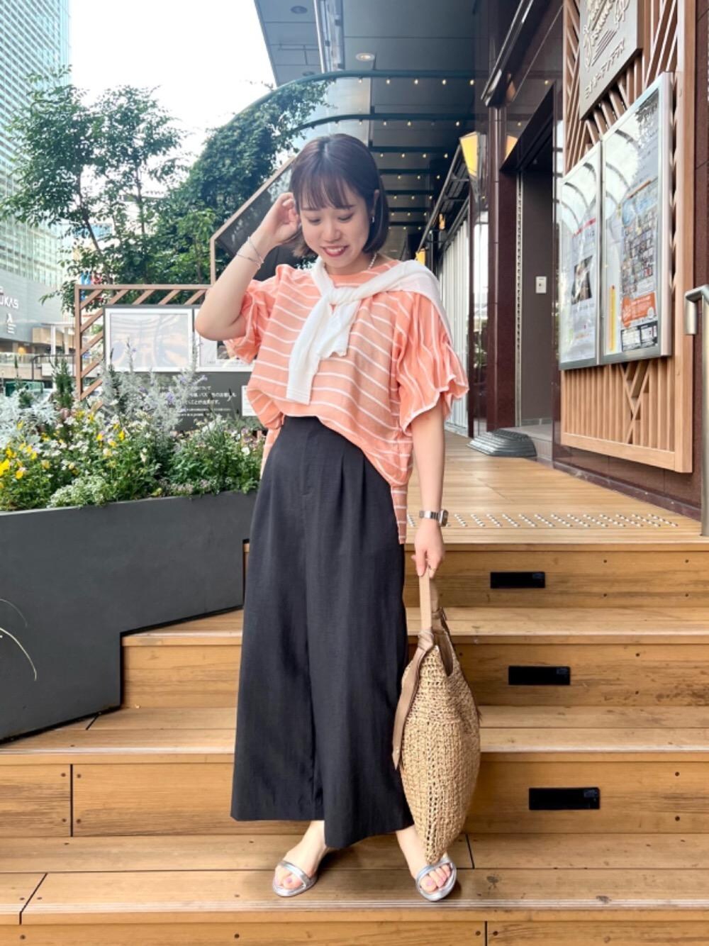 シルバー系のサンダル、ホワイト系のカーディガン/ボレロ、ベージュ系のかごバッグを着用したレディースの春コーディネートの1枚目の写真