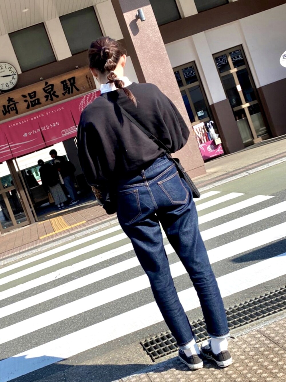 ブルー系のデニムパンツ、ブラック系のスニーカー、ホワイト系のソックス/靴下を着用したレディースの春コーディネートの1枚目の写真