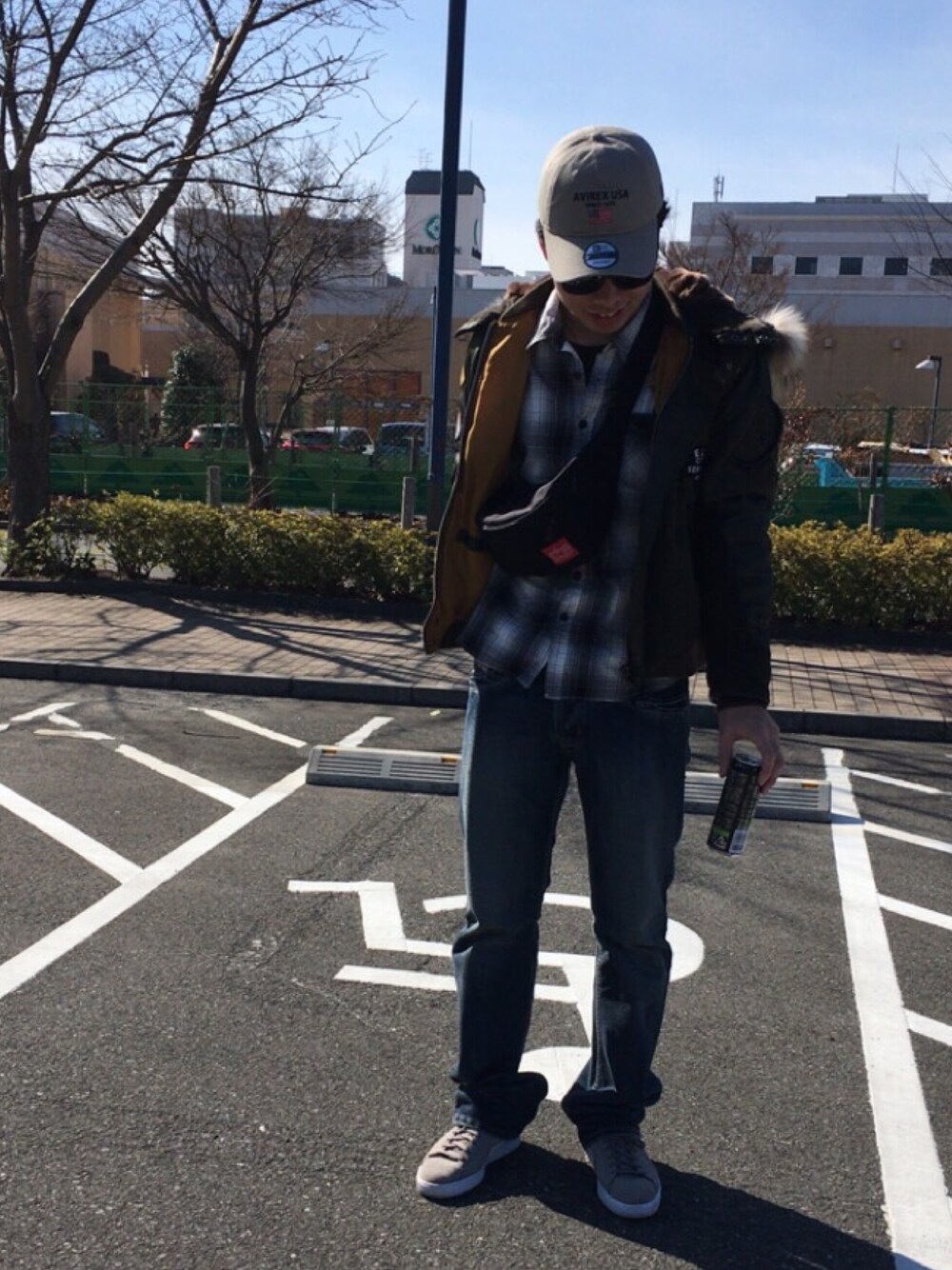 グリーン系のミリタリージャケット、ブラック系のボディバッグ/ウエストポーチ、グレー系のスニーカーを着用したメンズの春コーディネートの1枚目の写真