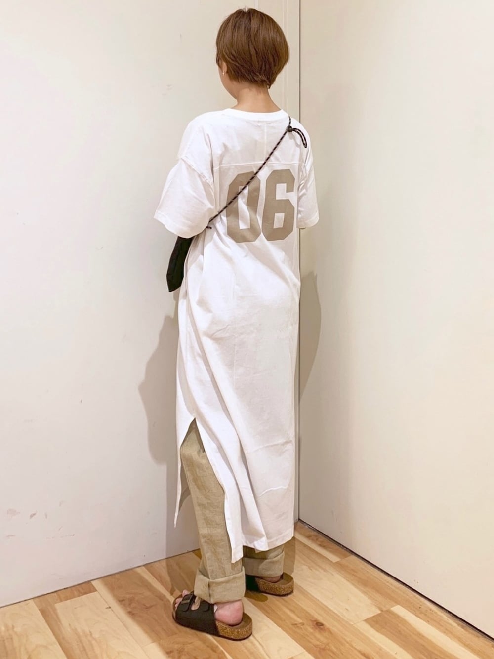 ブルー系のバックパック/リュック、ベージュ系のTシャツ/カットソー、ホワイト系のシャツワンピースを着用したレディースの夏コーディネートの1枚目の写真