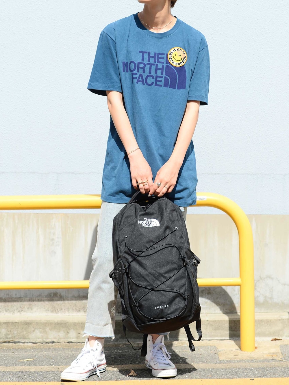 ブラック系のバックパック/リュック、ブルー系のTシャツ/カットソー、ホワイト系のスニーカーを着用したレディースの夏コーディネートの1枚目の写真