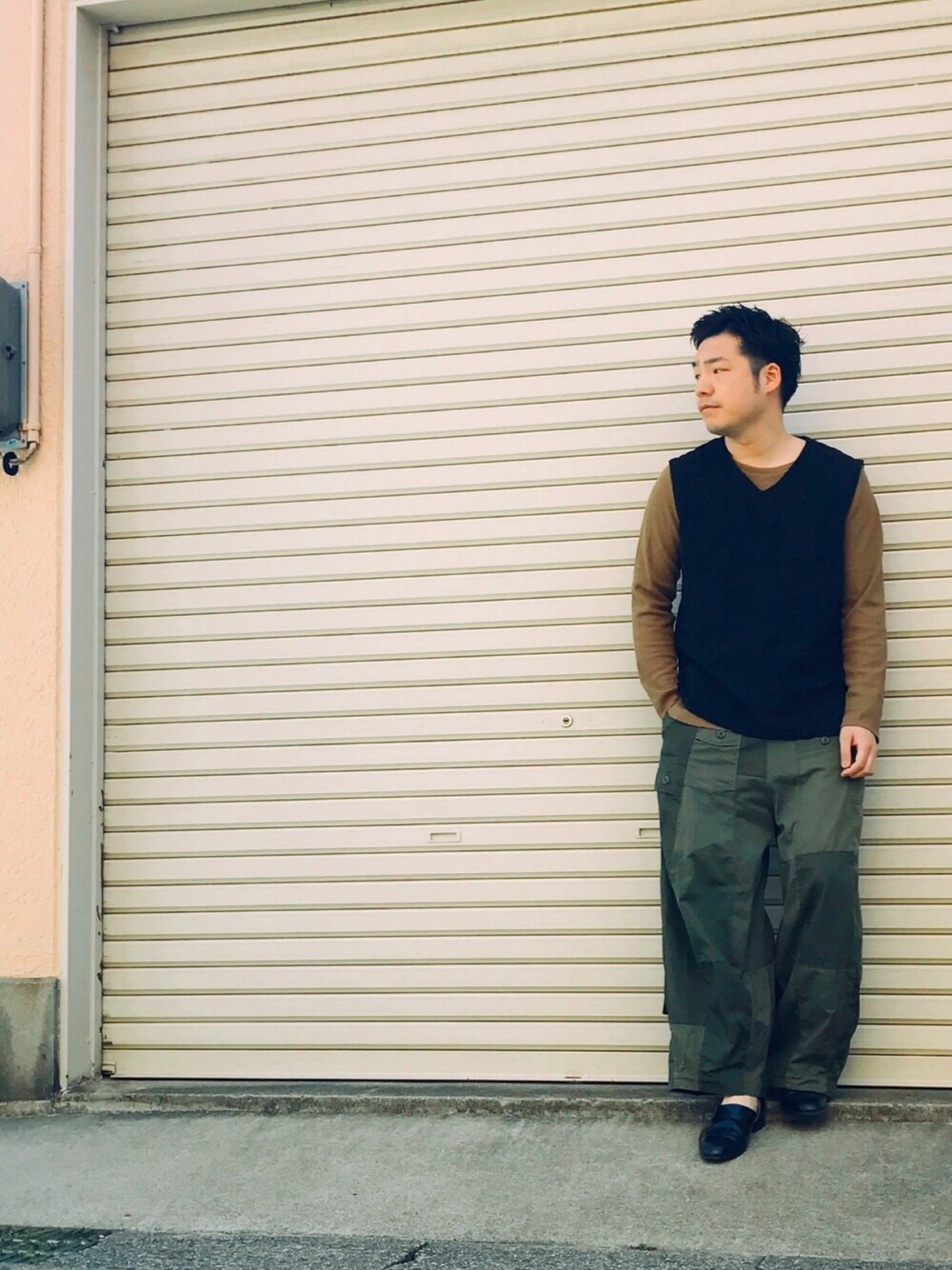 イエロー系のTシャツ/カットソー、ブラック系のベスト、グリーン系のパンツを着用したメンズの夏コーディネートの1枚目の写真