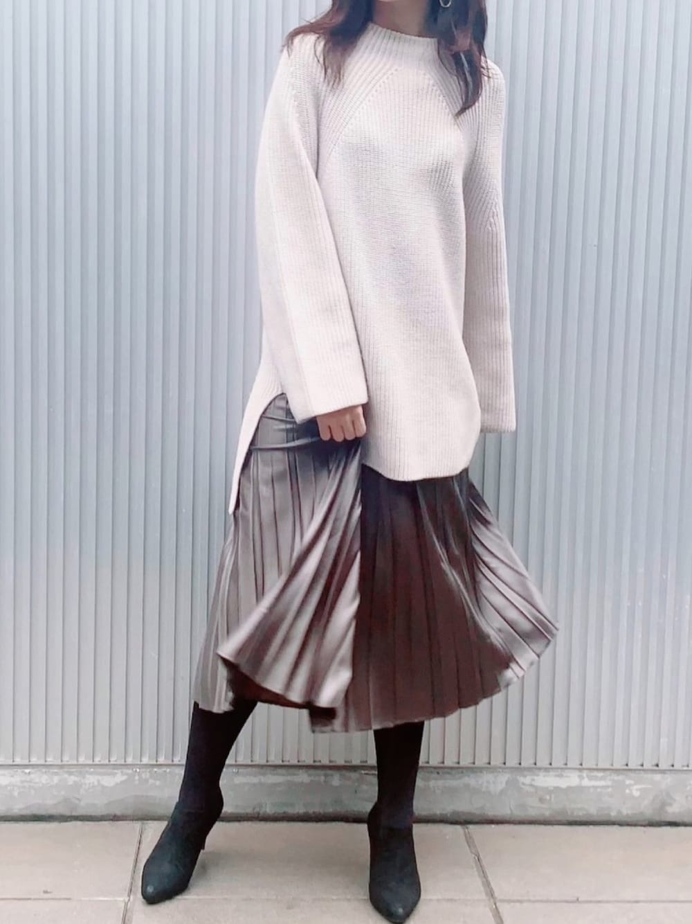 ホワイト系のニット/セーター、グリーン系のスカート、ブラック系のブーティを着用したレディースの冬コーディネートの1枚目の写真