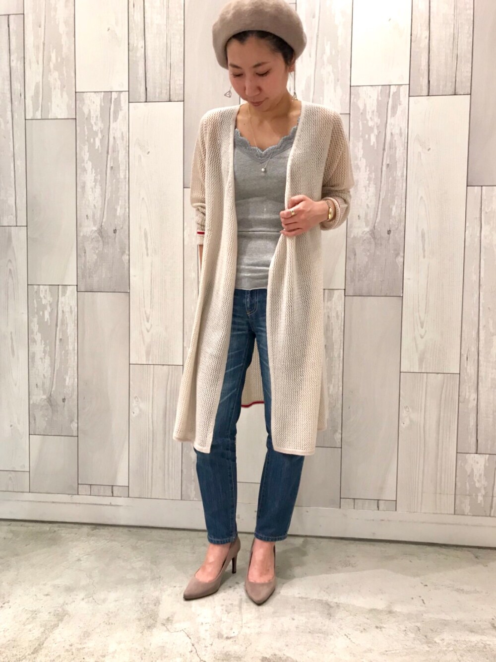 グレー系のタンクトップ、ベージュ系のカーディガン/ボレロ、ブルー系のデニムパンツを着用したレディースの冬コーディネートの1枚目の写真