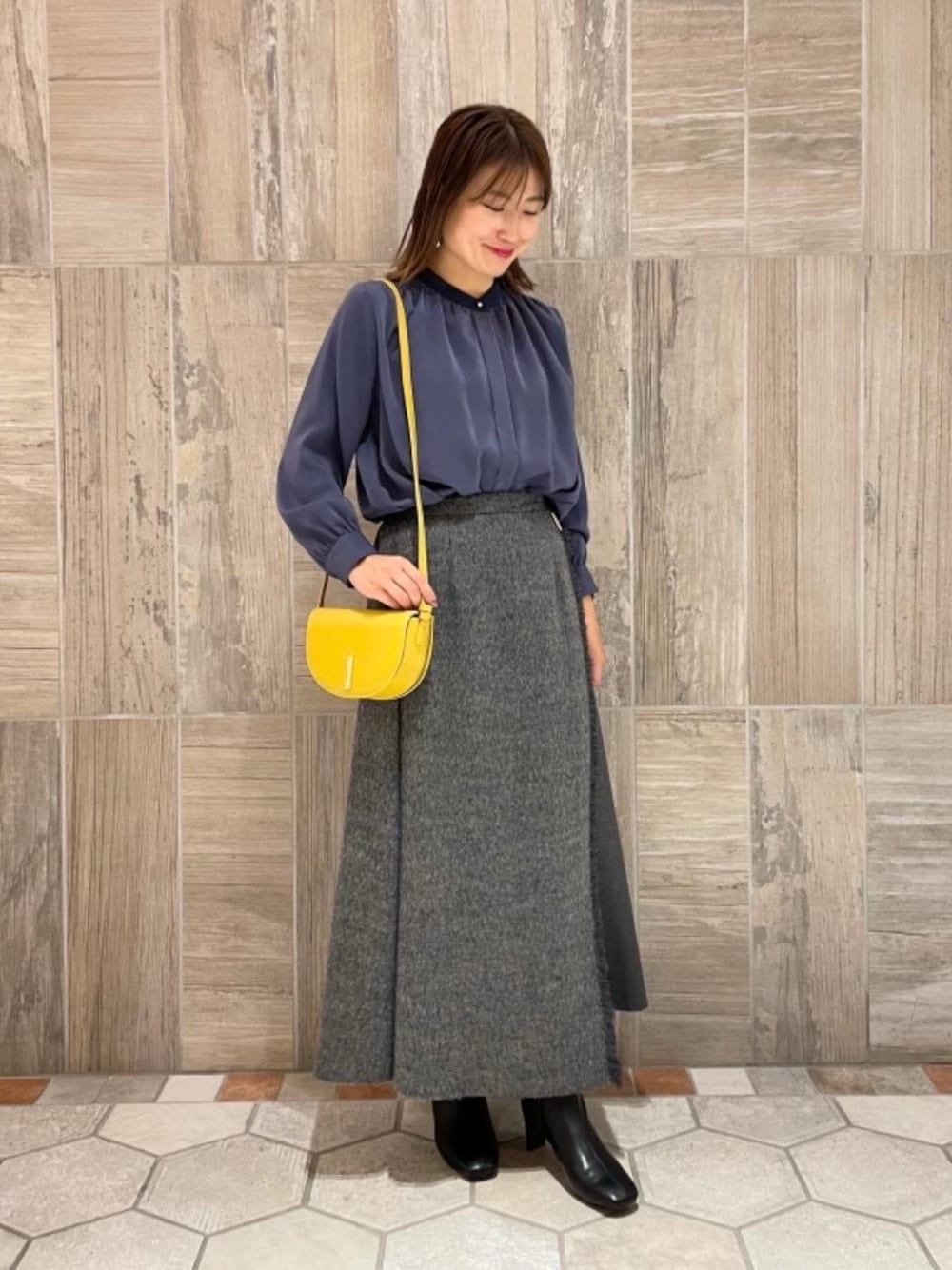 イエロー系のショルダーバッグ、グレー系のスカート、ブルー系のシャツ/ブラウスを着用したレディースの秋コーディネートの1枚目の写真