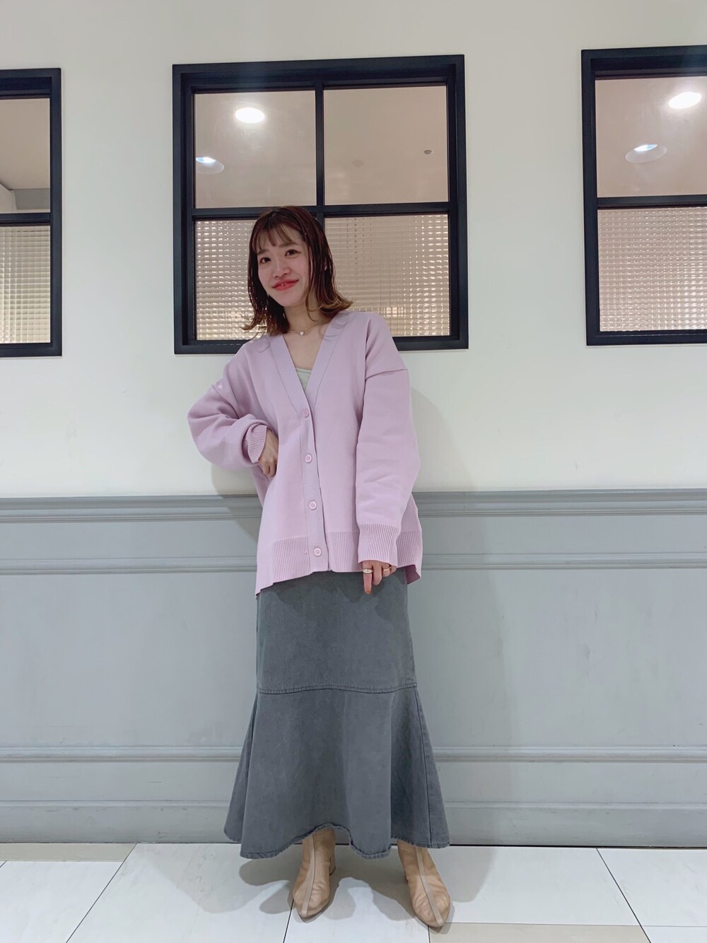 ピンク系のカーディガン/ボレロ、グレー系のスカート、ベージュ系のブーツを着用したレディースの春コーディネートの1枚目の写真