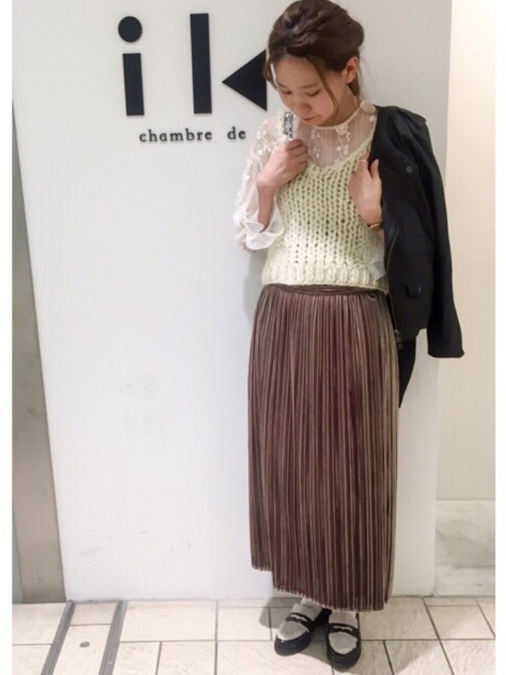 ベージュ系のスカート、ホワイト系のニット/セーター、ブラック系のライダースジャケットを着用したレディースの秋コーディネートの1枚目の写真