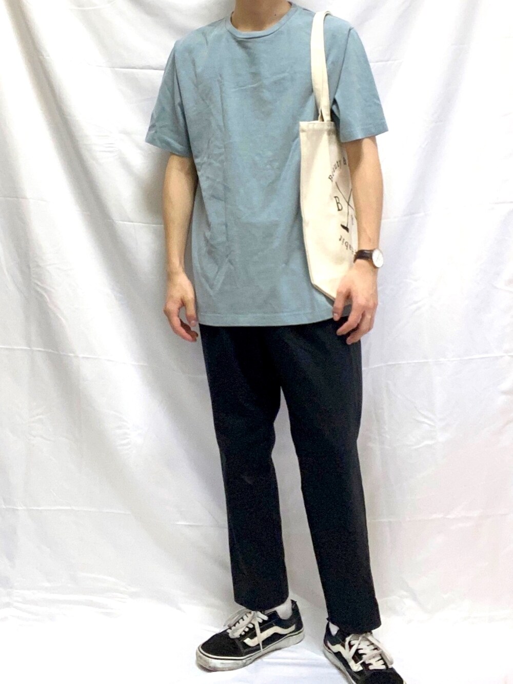 ブルー系のTシャツ/カットソー、ブラック系のスラックス、ベージュ系のトートバッグを着用したメンズの夏コーディネートの1枚目の写真