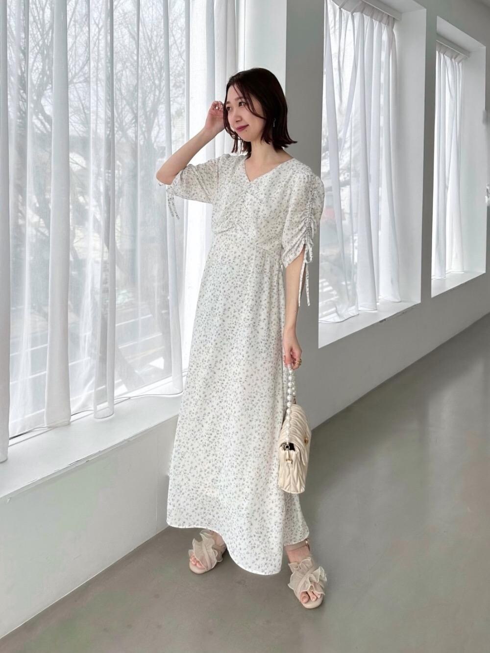 ホワイト系のショルダーバッグ、ホワイト系のワンピース、ベージュ系のサンダルを着用したレディースの春コーディネートの1枚目の写真