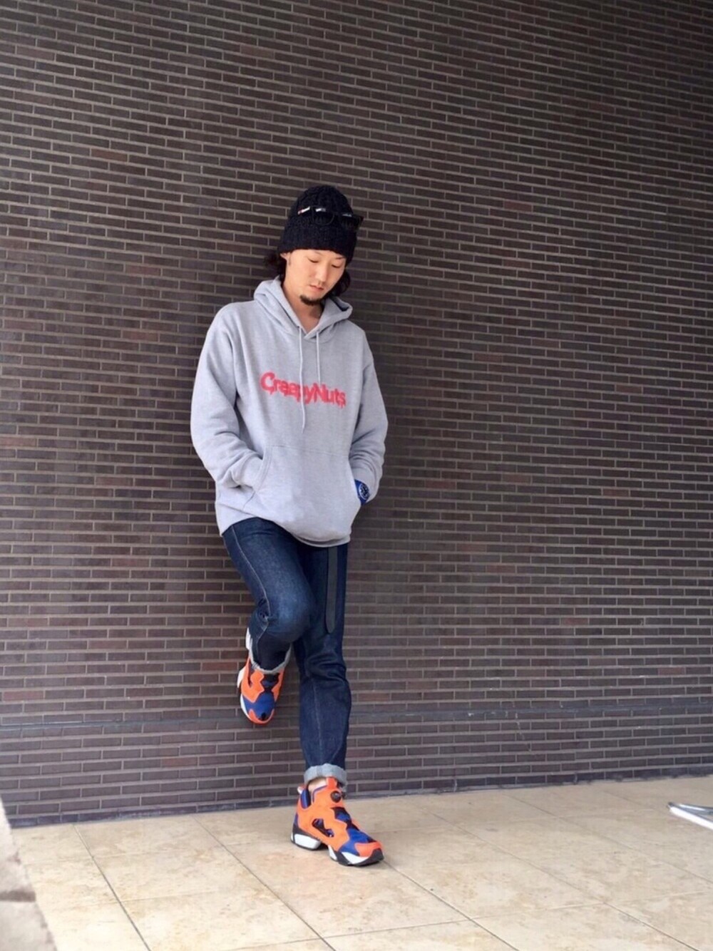 グレー系のパーカー、ブルー系のデニムパンツ、オレンジ系のスニーカーを着用したメンズの春コーディネートの1枚目の写真