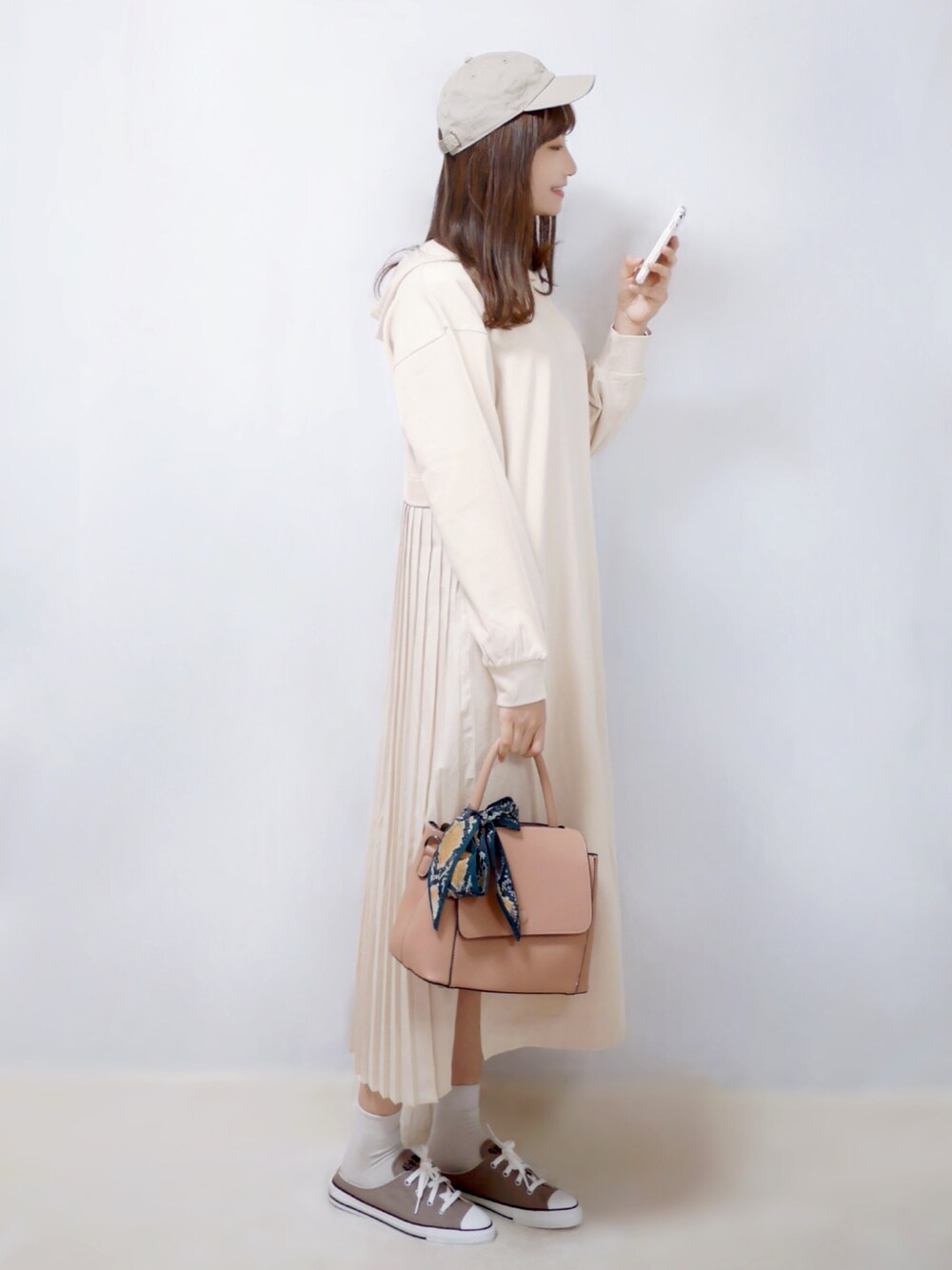 ベージュ系のワンピース、ピンク系のショルダーバッグ、グレー系のスニーカーを着用したレディースの春コーディネートの1枚目の写真