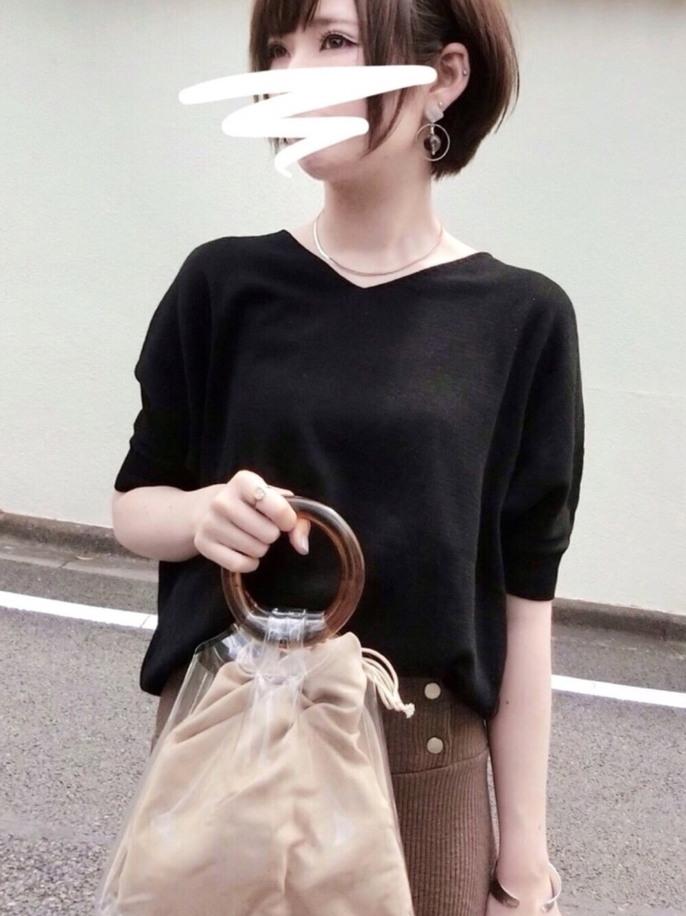 ブラック系のニット/セーター、ブラウン系のスカート、パープル系のハンドバッグを着用したレディースの春コーディネートの1枚目の写真