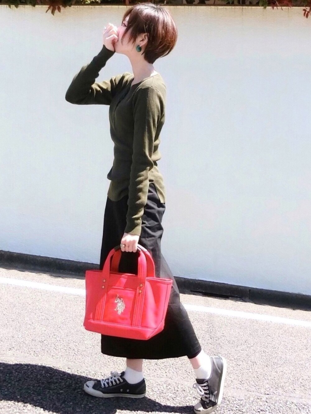 レッド系のトートバッグ、ブラウン系のニット/セーター、ブラック系のスカートを着用したレディースの春コーディネートの1枚目の写真