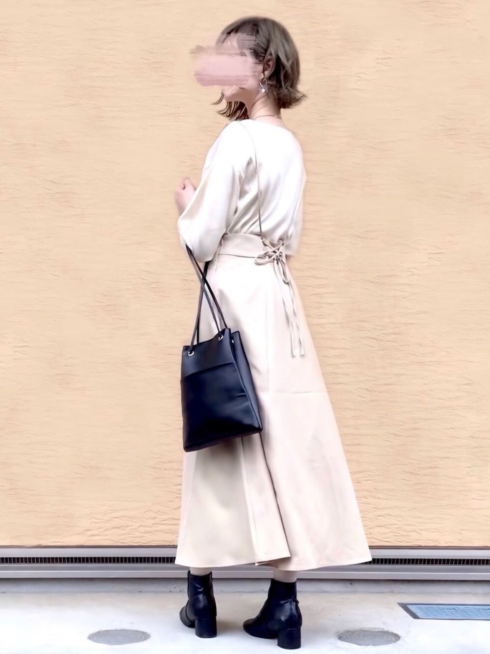 ベージュ系のスカート、ホワイト系のニット/セーター、ブラック系のブーツを着用したレディースの春コーディネートの1枚目の写真