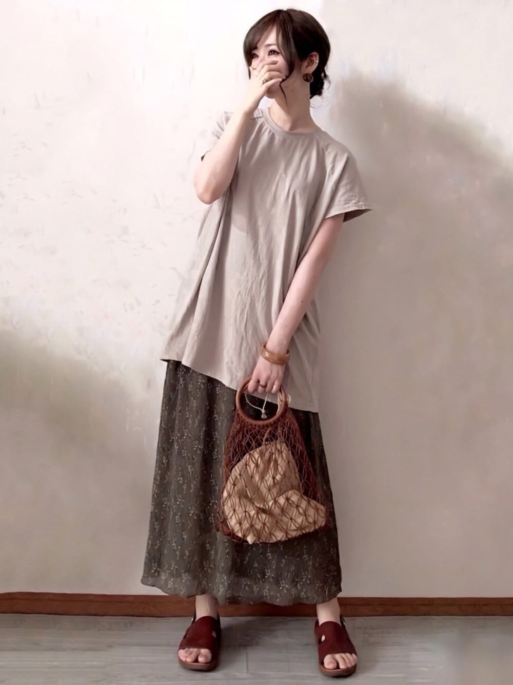 グリーン系のTシャツ/カットソー、グリーン系のスカート、ベージュ系のサンダルを着用したレディースの夏コーディネートの1枚目の写真