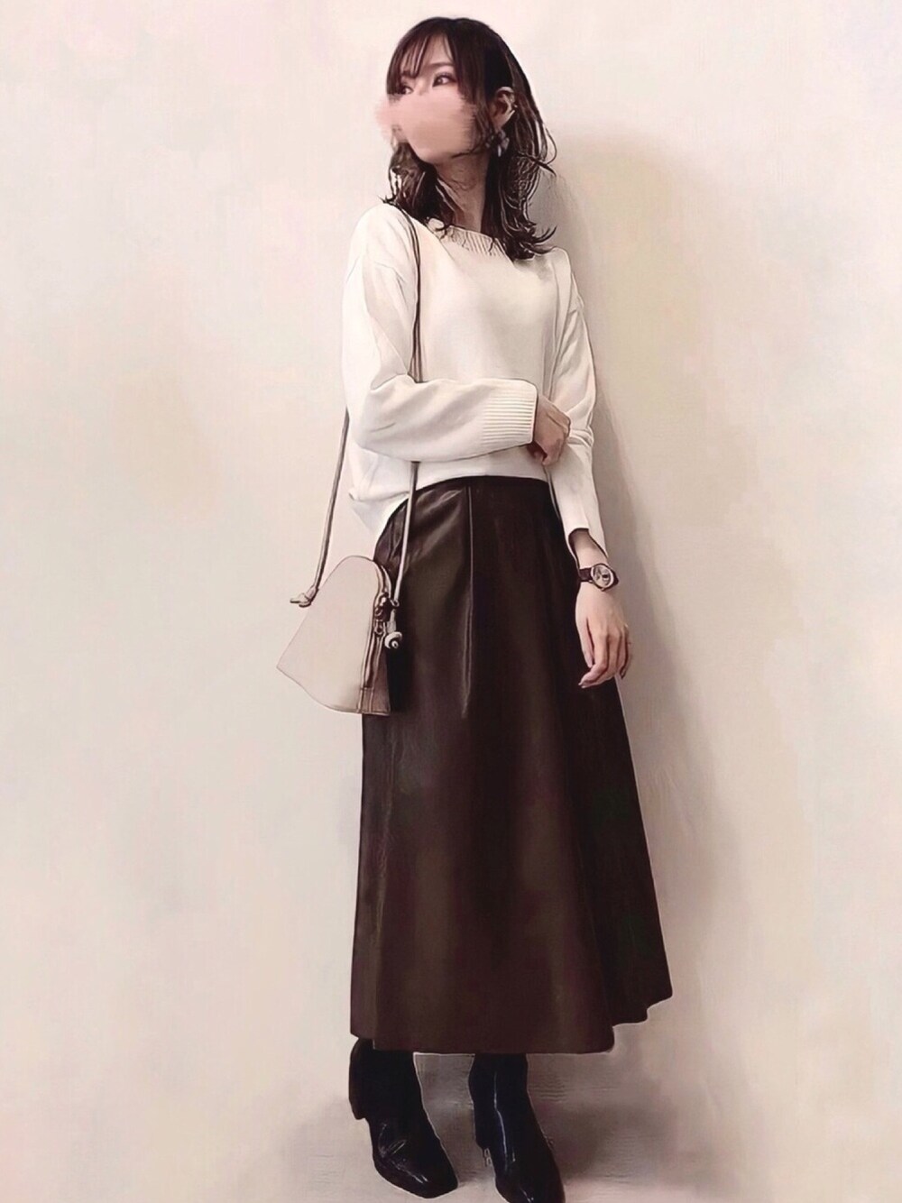ホワイト系のニット/セーター、ブラウン系のスカート、ブラック系のブーツを着用したレディースの春コーディネートの1枚目の写真