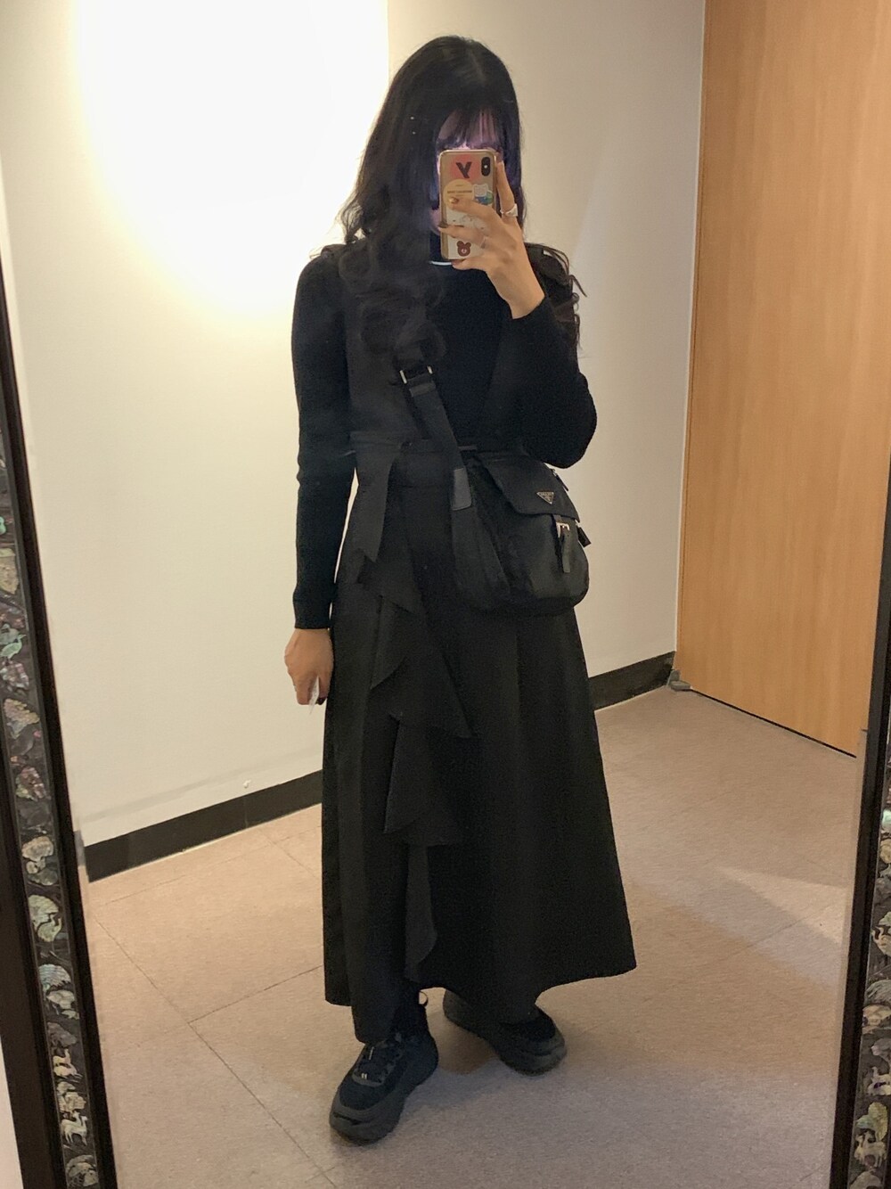 ブラック系のニット/セーター、ブラック系のショルダーバッグ、ブラック系のジャンパースカートを着用したレディースの冬コーディネートの1枚目の写真