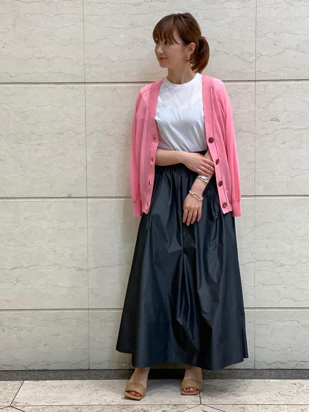 グレー系のスカート、ピンク系のカーディガン/ボレロ、シルバー系のブレスレットを着用したレディースの春コーディネートの1枚目の写真