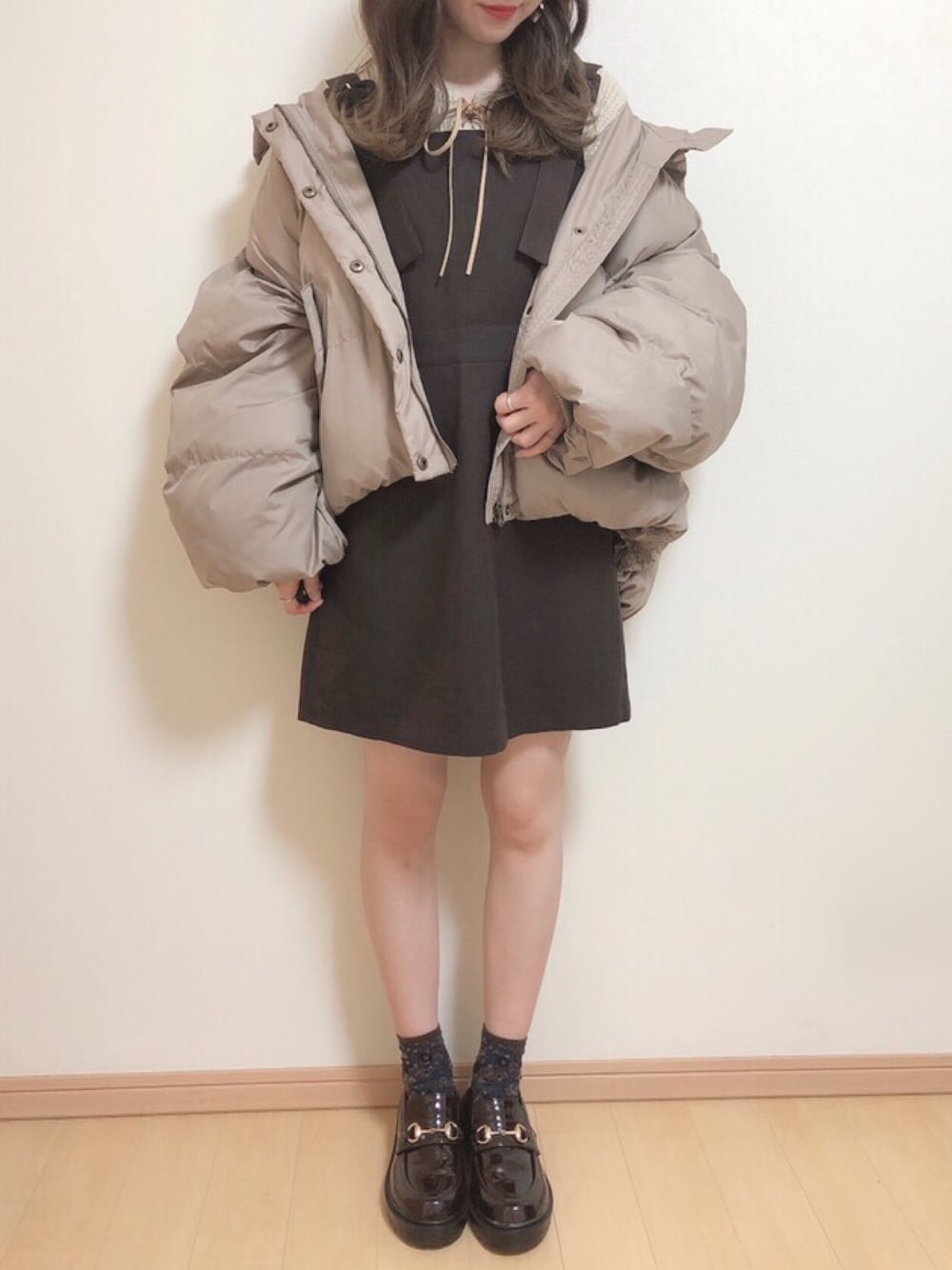 ホワイト系のニット/セーター、ブラウン系のジャンパースカート、ブラウン系のブルゾンを着用したレディースの秋コーディネートの1枚目の写真