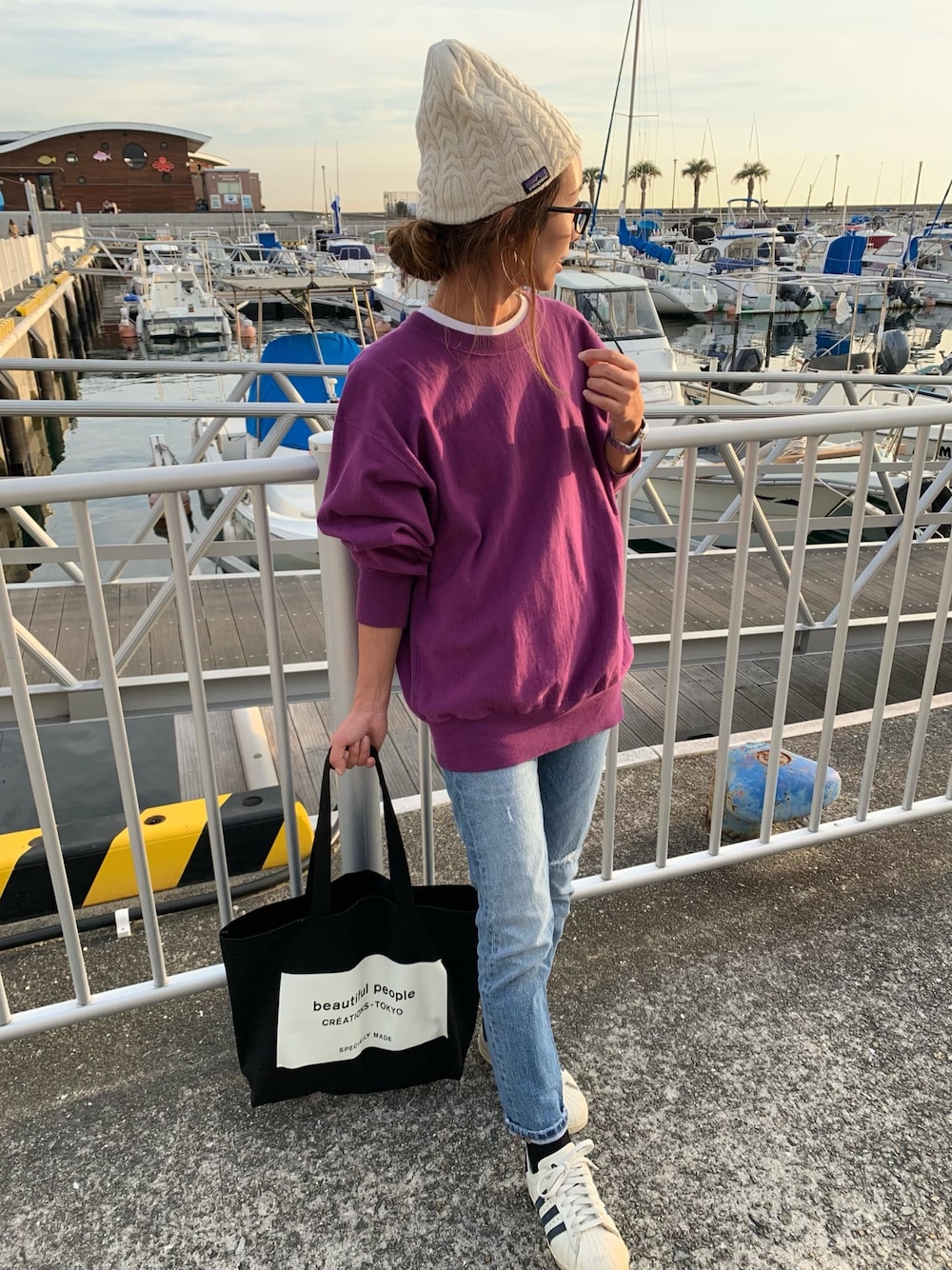 パープル系のスウェット、ブルー系のデニムパンツ、ホワイト系のスニーカーを着用したレディースの冬コーディネートの1枚目の写真