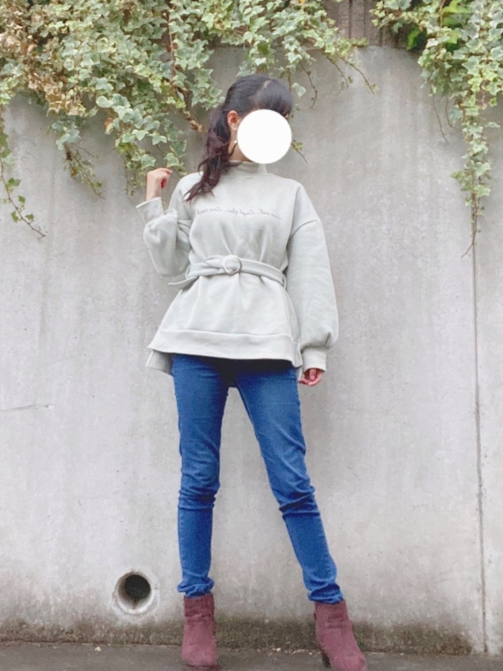 グリーン系のトップス、ブルー系のパンツ、ブラウン系のブーツを着用したレディースの秋コーディネートの1枚目の写真