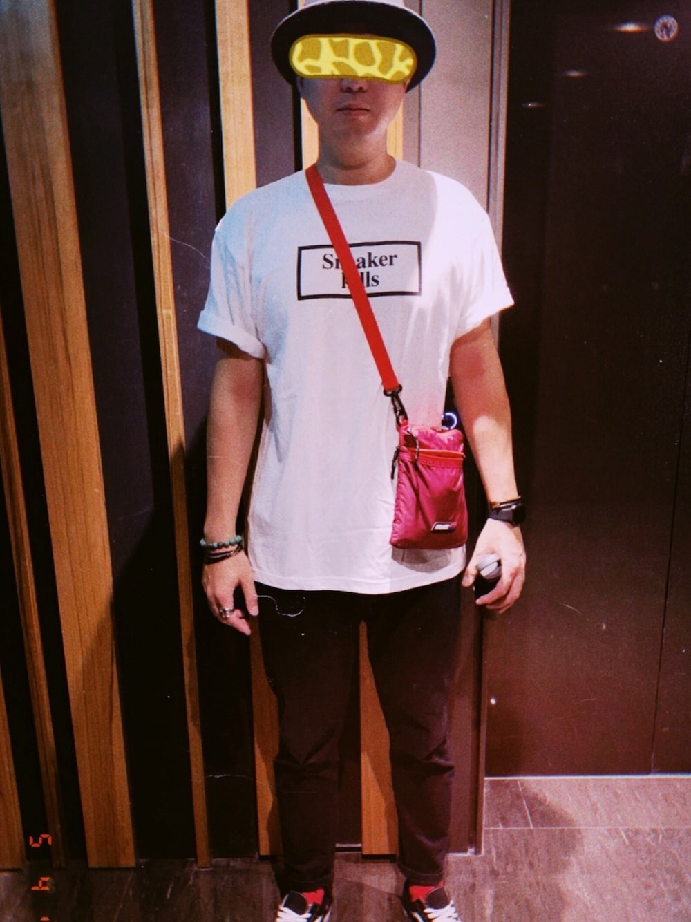 レッド系のショルダーバッグ、ホワイト系のTシャツ/カットソー、ブラック系のハットを着用したメンズの春コーディネートの1枚目の写真